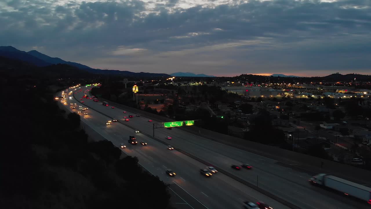Night Traffic on Highway with City and Mountain Views