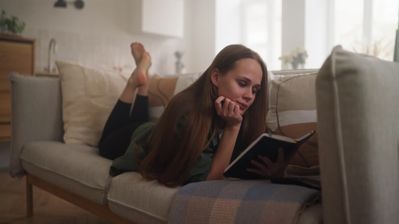 mujer relajándose en el sofá leyendo un libro