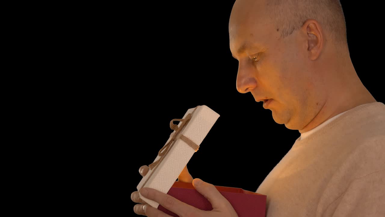 un hombre feliz recibió un regalo. el hombre miró en la caja de regalos y se inspiró mucho. un hombre alegre está muy agradecido por el regalo. vista lateral bloqueo. canal alfa clave de croma fondo transparente.