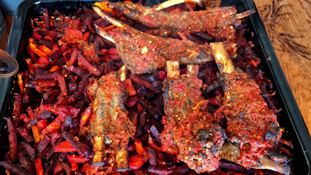 A wooden spoon scoops up meat from a smokey barbecue grill with spicy ribs, close up