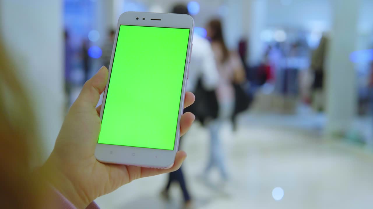 거리에서 초록색 화면을 가진 스마트폰을 사용하는 여성