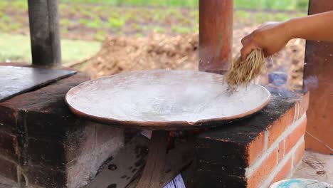 Mujer-Mexicana-Curando-Un-Comal-De-Arcilla-Artesanal-Vistiendo-Ropa-Típica