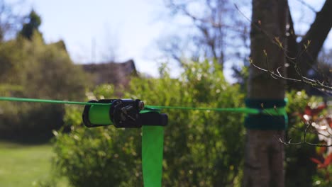 closeup of bright green slack line and ratchet on slightly windy but very sunny day