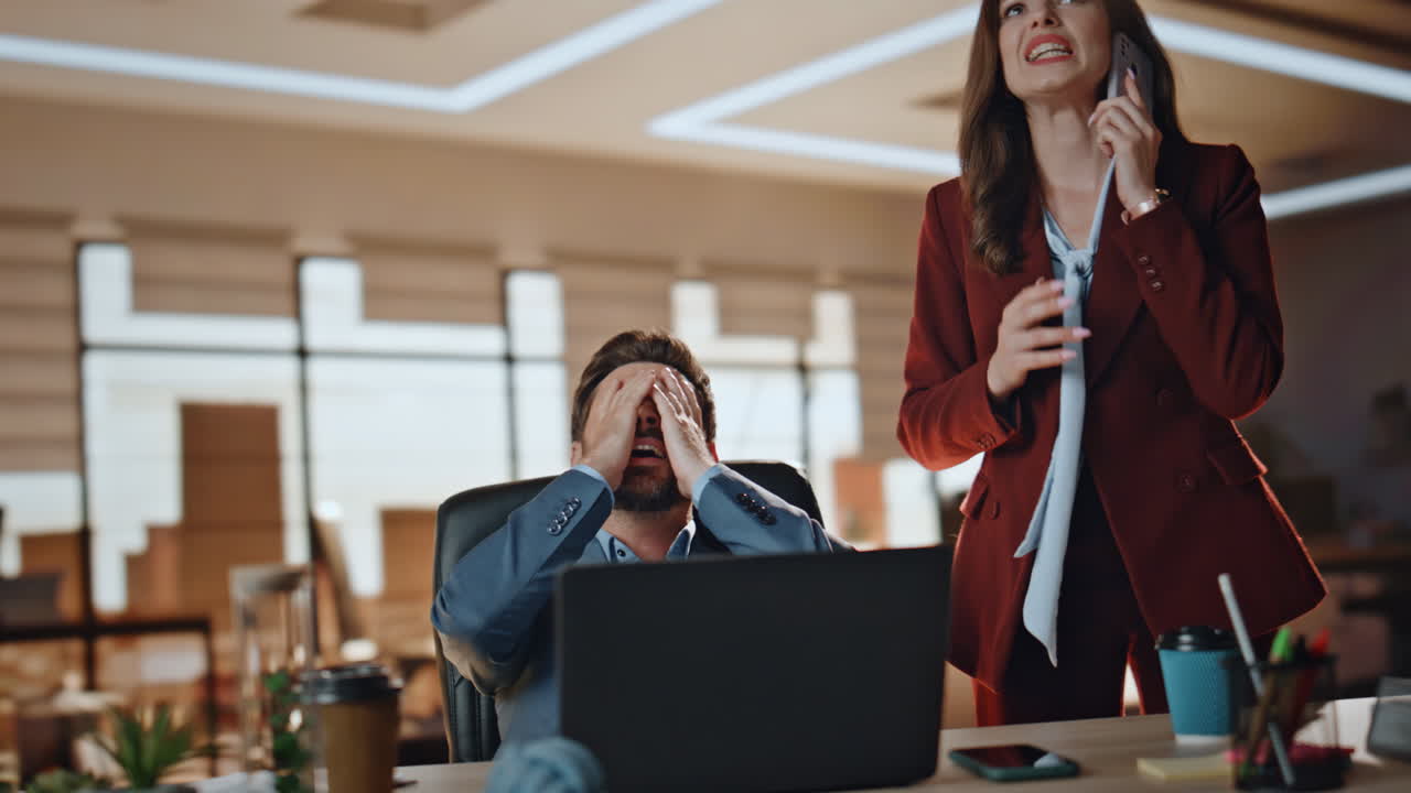 una pareja de negocios estresada trabajando en un gran gabinete. una mujer nerviosa llama por teléfono inteligente.