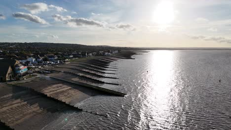 Whitstable-beach-groins-Kent-UK-Drone,-Aerial,-into-setting-sun-4K