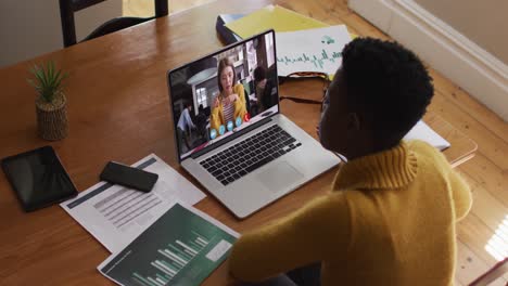 African-american-woman-talking-and-taking-notes-while-having-a-video-call-on-laptop-at-home