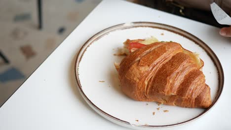 persona comiendo un sándwich de croissant