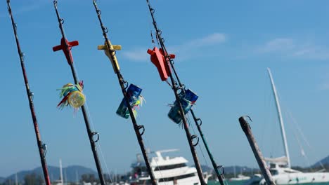 fishing rods with colorful lures sway on a boat under clear skies in phuket, thailand, capturing a serene maritime scene