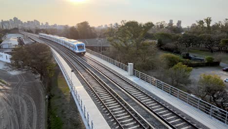 Close-up-shot-of-railroad-infrastructure-with-argentina-public-transportation-mitre-train-departing-from-downtown-Buenos-Aires-city-at-sunset