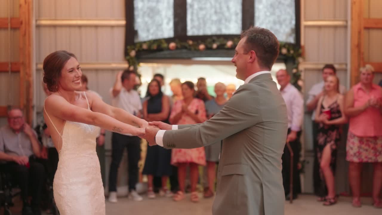 Bride and groom share romantic kiss after first dance as guests clap and take photos