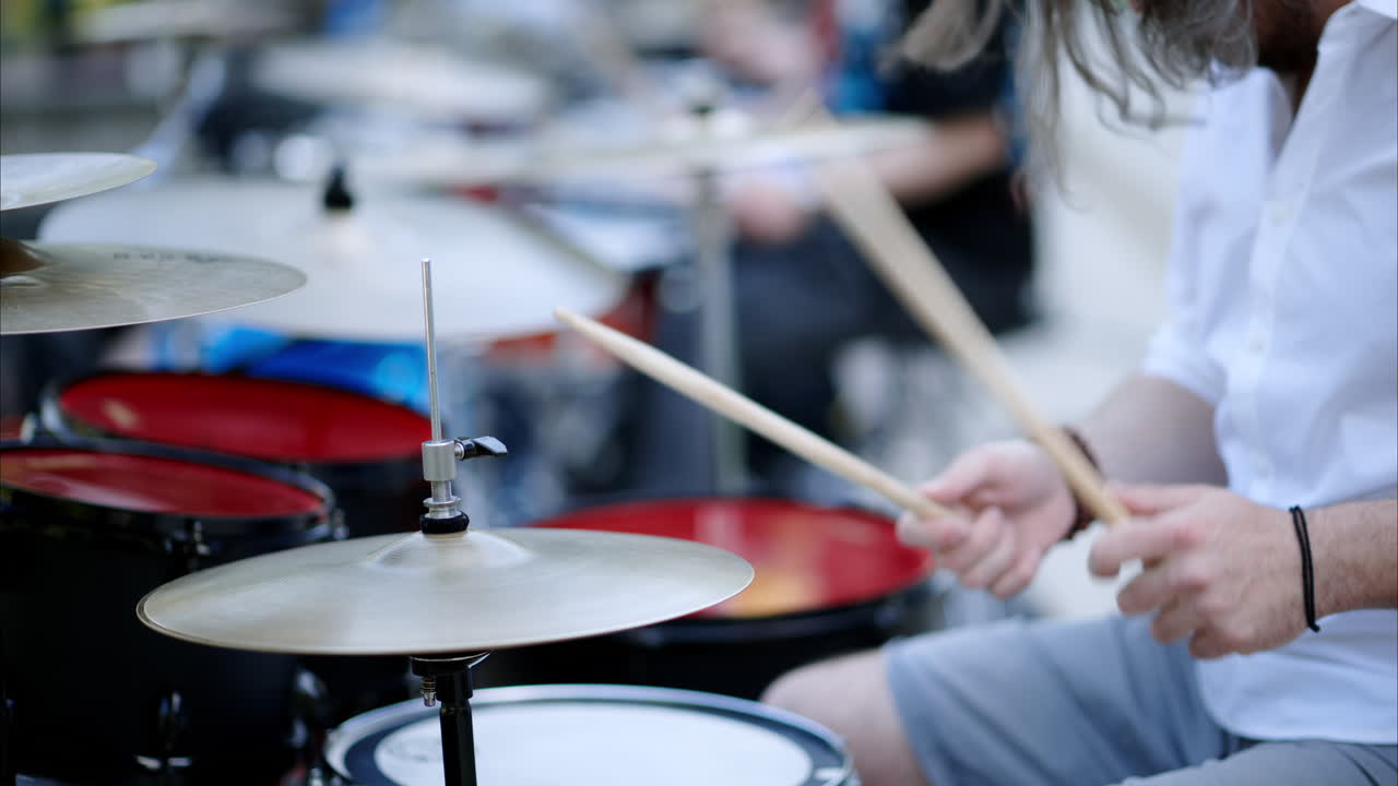 Close up of man playing red drums outside