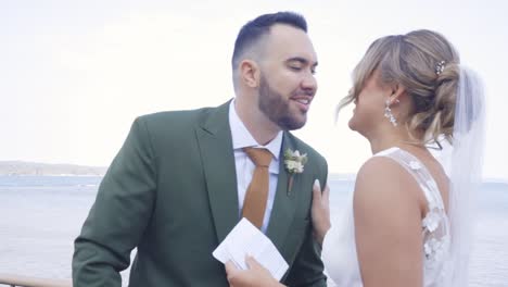 groom kisses his bride in front of water
