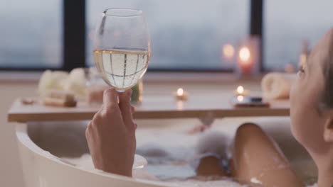 camera focuses on a woman holding a glass of wine and drinking