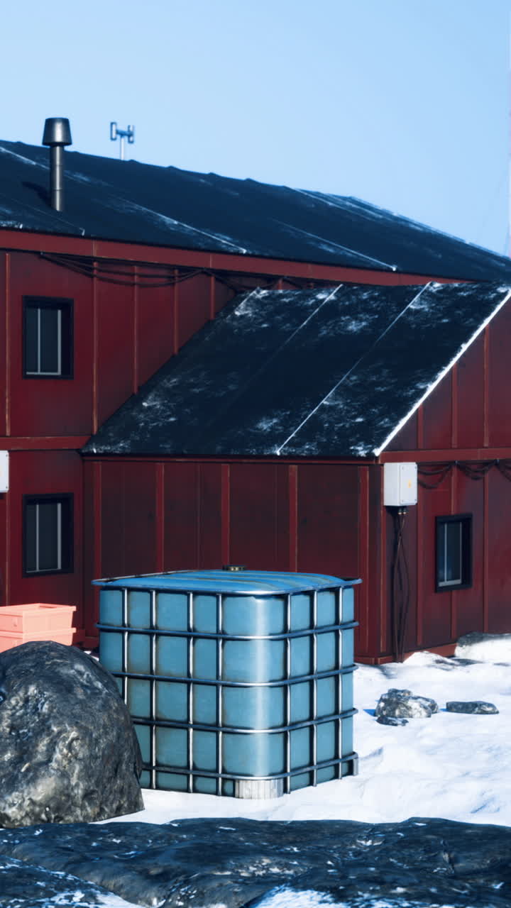 Red structure in snowy landscape with water storage tank under clear sky
