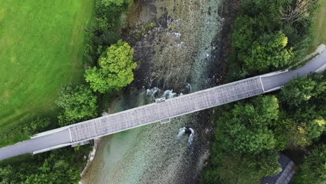 Wooden-bridge-over-a-picturesque-river-in-Austria,-top-down-drone-shot