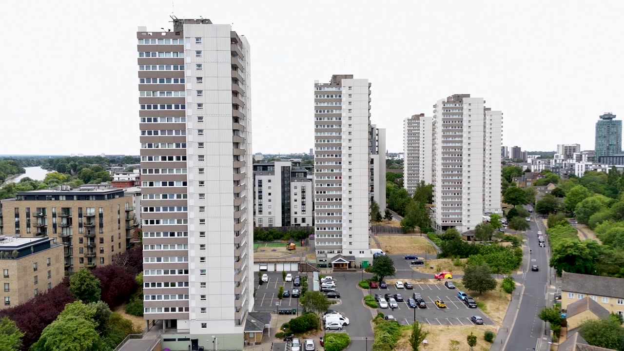 Blocos de torres do pós-guerra erguem-se acima de um conjunto habitacional arborizado, com o subúrbio estendendo-se até o horizonte