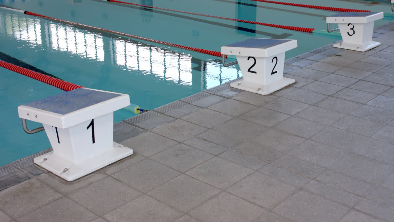 Blocos de partida na beira de uma piscina, prontos para uma corrida.