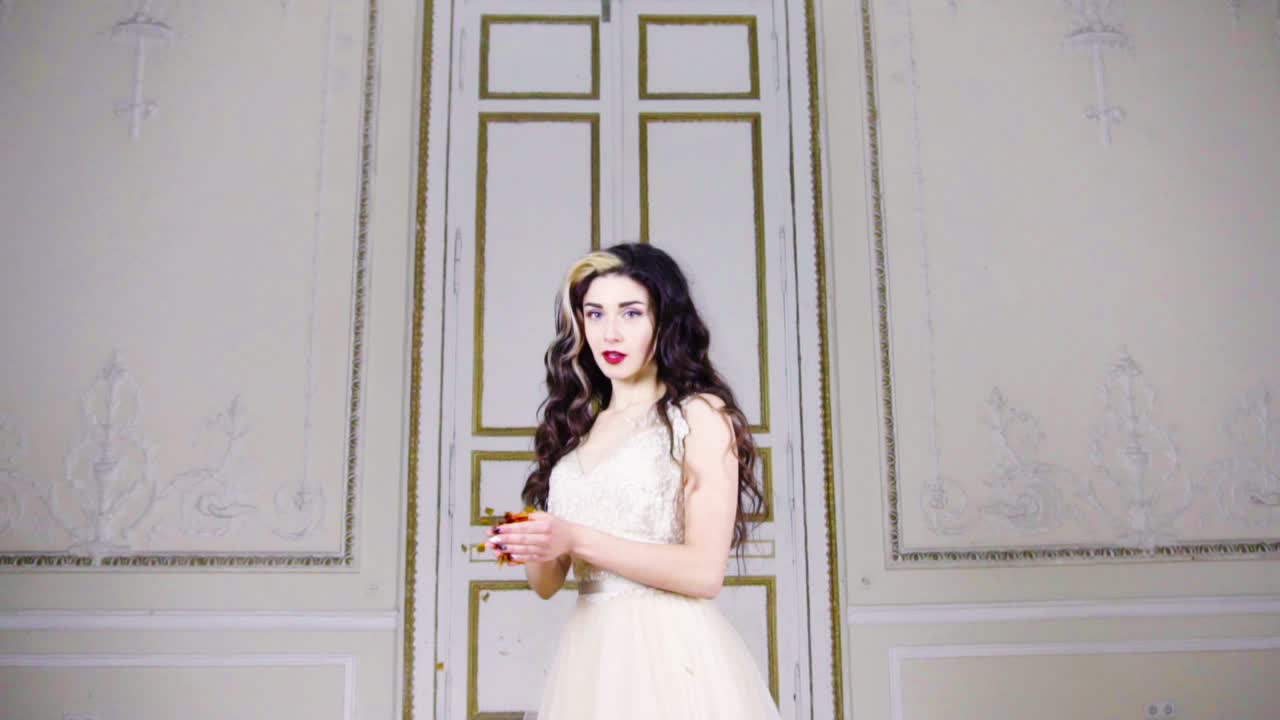 молодая брюнетка с красными губами выдувает золотое конфетти