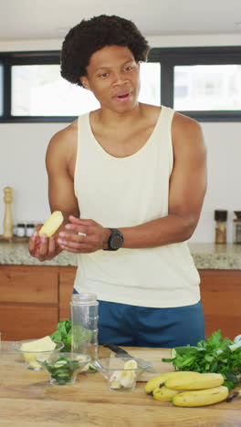 video vertical de un vlogger de fitness afroamericano preparando una bebida para la salud, hablando con la cámara