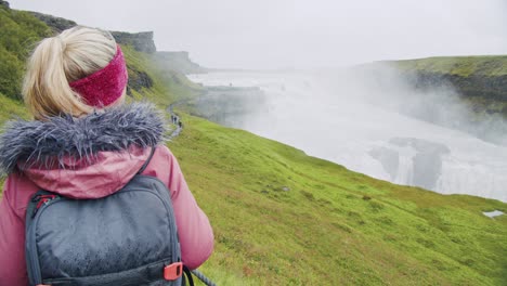 vista trasera de una mujer turista mirando la cascada gullfoss la famosa atracción y destino histórico de islandia en el círculo dorado