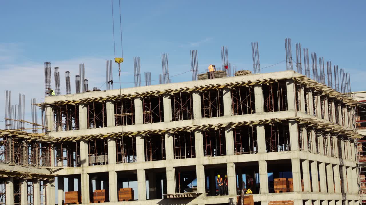 Construction workers in uniform installing and fabricating ground beam timber form works at the construction site under tower crane