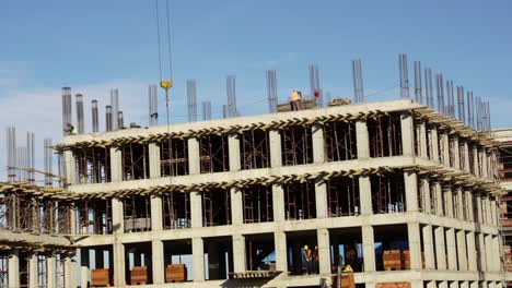 construction workers in uniform installing and fabricating ground beam timber form works at the construction site under tower crane