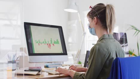 mujer con máscara facial usando computadora en la oficina