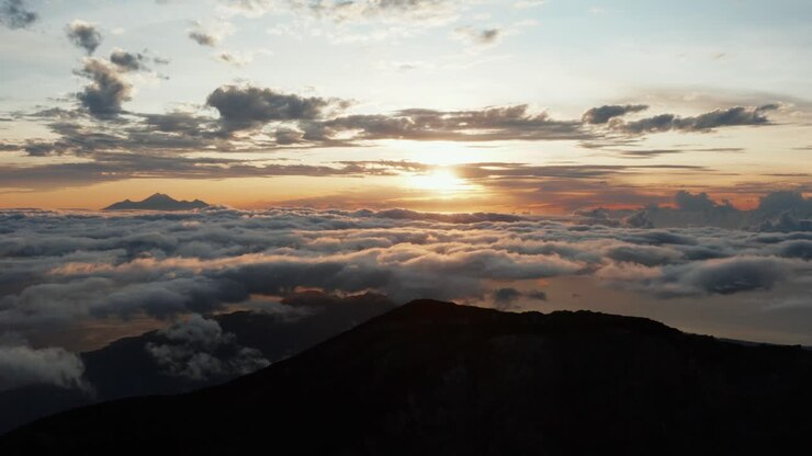 Dron Volando sobre la Cima de la Montaña al Amanecer. Movimiento Hacia Adelante. Silueta de montaña al fondo. Metraje 4k