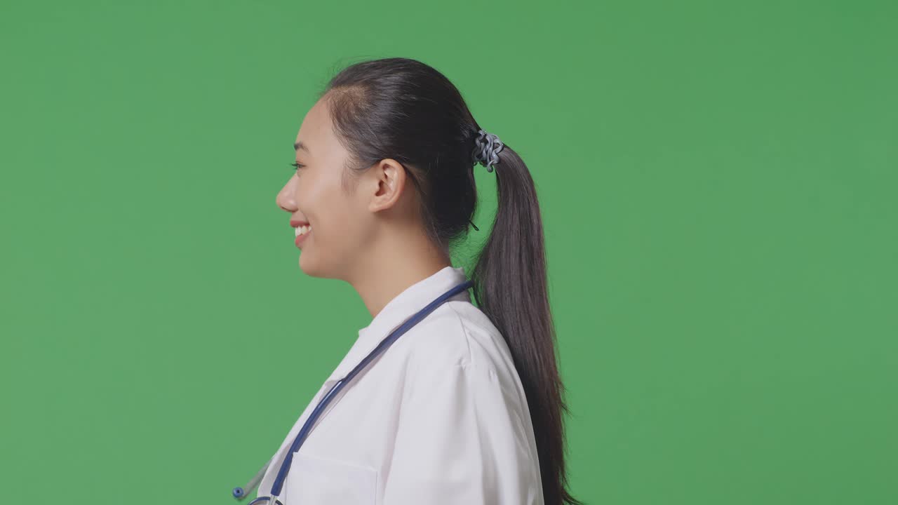 Close Up Of Side View Asian Female Doctor With Stethoscope Looking Around And Walking On Green Screen Background In The Hospital