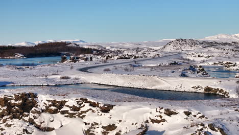 Lone-car-drives-isolated-road-along-Myvatn-lake-in-Iceland,-aerial