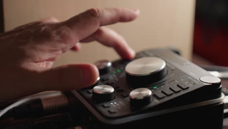 close-up of a hand carefully adjusting the knobs on a sound mixer to fine-tune audio levels. with the sound mixer s controls and indicators clearly visible