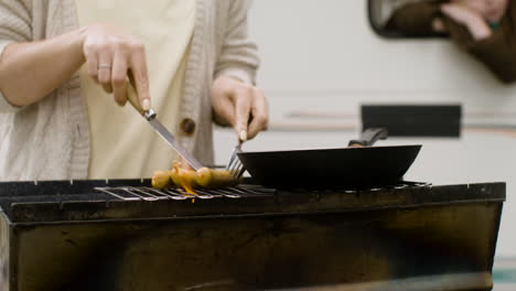 close up of an unrecognizable woman cooking sausages on barbecue grill outdoors