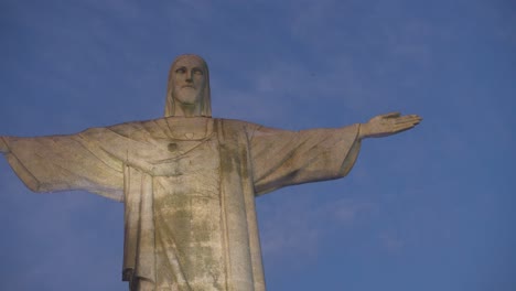 christ the redeemer statue in rio de janeiro, arms outstretched against blue sky