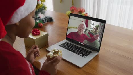 Mujer-Afroamericana-Con-Sombrero-De-Santa-Usando-Una-Computadora-Portátil-Para-Una-Videollamada-Navideña-Con-Un-Hombre-En-La-Pantalla