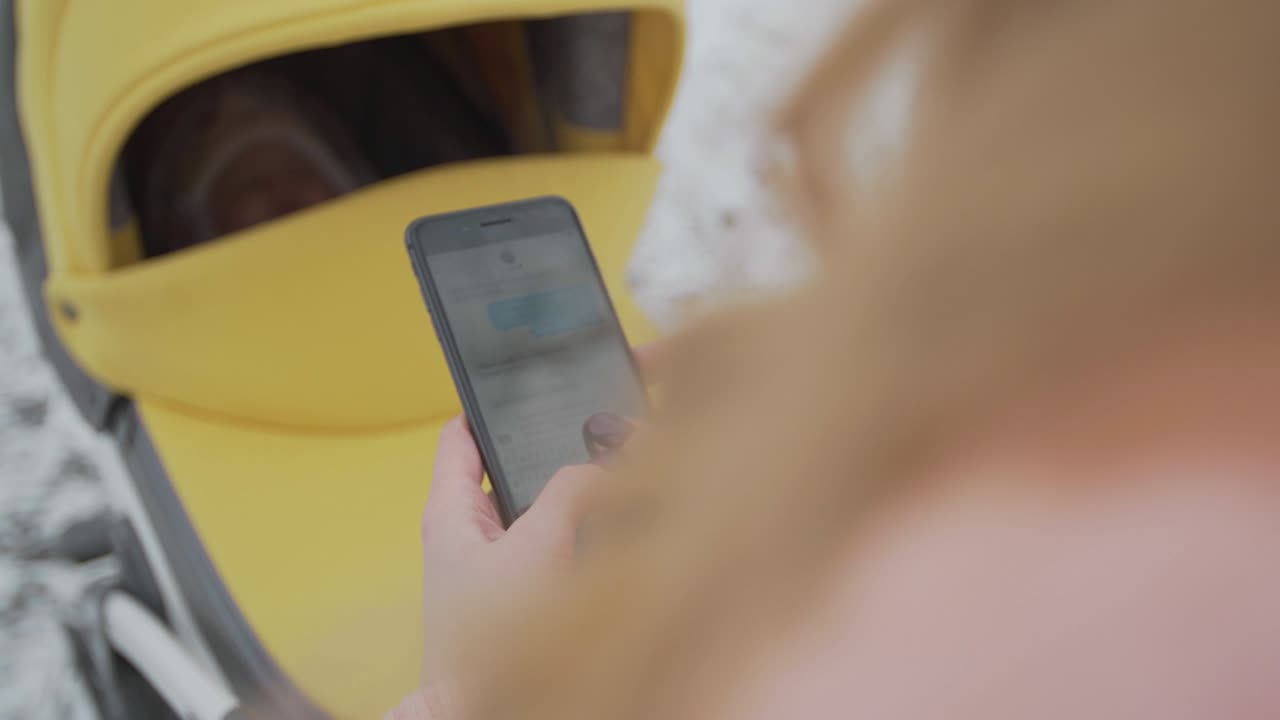 una mujer joven escribe y desliza en su teléfono inteligente en el parque de invierno. teléfono celular con pantalla de teclas cromadas - pantalla verde. cerrar. seguimiento de movimiento.