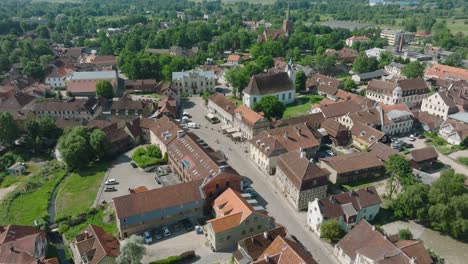 Aerial-establishing-view-of-Kuldiga-Old-Town-,-houses-with-red-roof-tiles,-sunny-summer-day,-travel-destination,-wide-drone-shot-moving-forward,-tilt-down