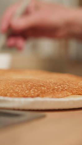 woman butters homemade pancake using white silicone brush. caring experienced grandmother cooks for grandchildren. delicious food making closeup