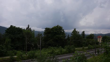 lapsos de tiempo de nubes en movimiento creando un cielo oscuro con relámpagos antes de la tormenta con nubes que aparecen y desaparecen formando un clima de mal humor en el campo con colinas y trenes en el fondo