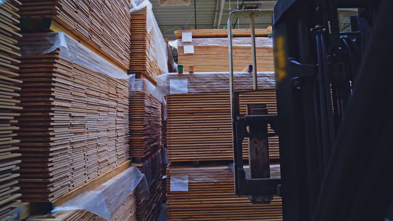Woodworking industry. Forklift cart putting stack of wooden boards on the floor. Modern factory of wood production. Camera motion back.