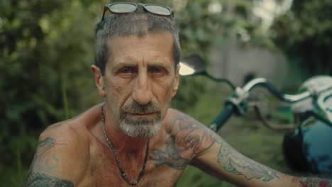 older man with tattoos by motorcycle