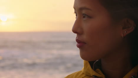 retrato de una mujer asiática feliz disfrutando de una contemplación pacífica explorando un estilo de vida despreocupado relajándose en la playa sintiéndose positiva al amanecer