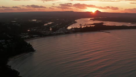 Puesta-De-Sol-épica-En-Australia-Desde-Un-Dron-Cerca-De-La-Costa-Y-El-Océano-Profundo-Y-Un-Pequeño-Pueblo-En-La-Parte-De-Atrás