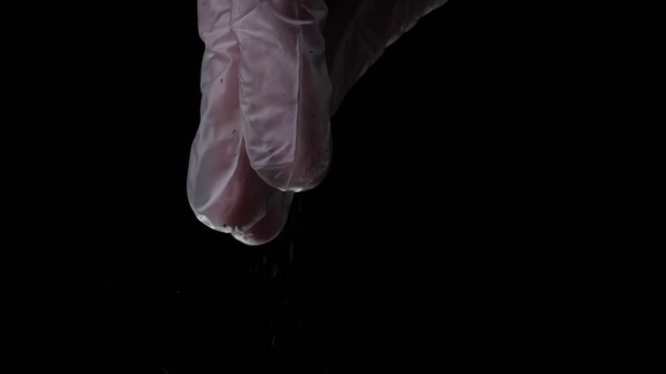 Pink Gloves Sprinkling Powder on Black Background
