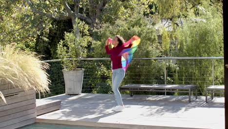 dancing with rainbow flag, woman celebrating outdoors on sunny day