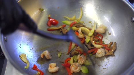 stir-frying shrimp and vegetables in a wok