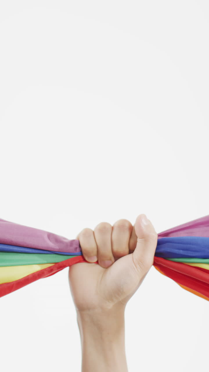 Vertical video of hand of caucasian woman holding rainbow fabric