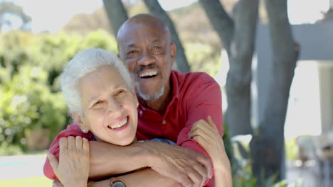 Portrait-of-happy-senior-biracial-couple-embracing-in-sunny-garden-at-home,-slow-motion