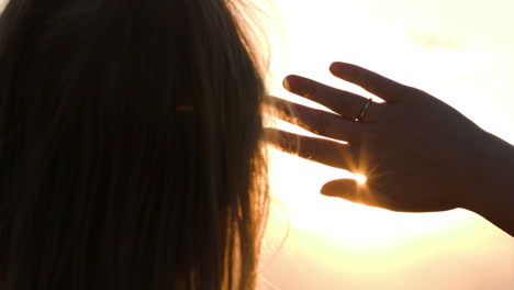 mujer mirando a la distancia escondiéndose del sol