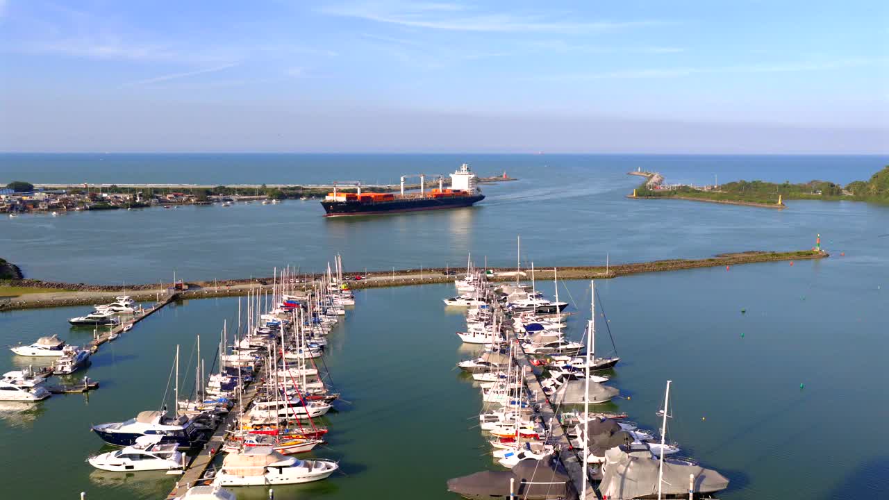 Cargo ship enters marina of Itajaí, Santa Catarina, Brazil, passing alongside rows of yachts and sailing boats