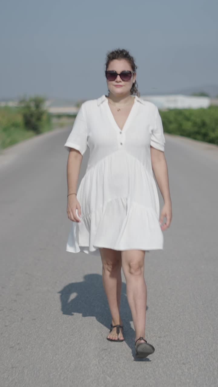 Donna in abito bianco che cammina sulla strada